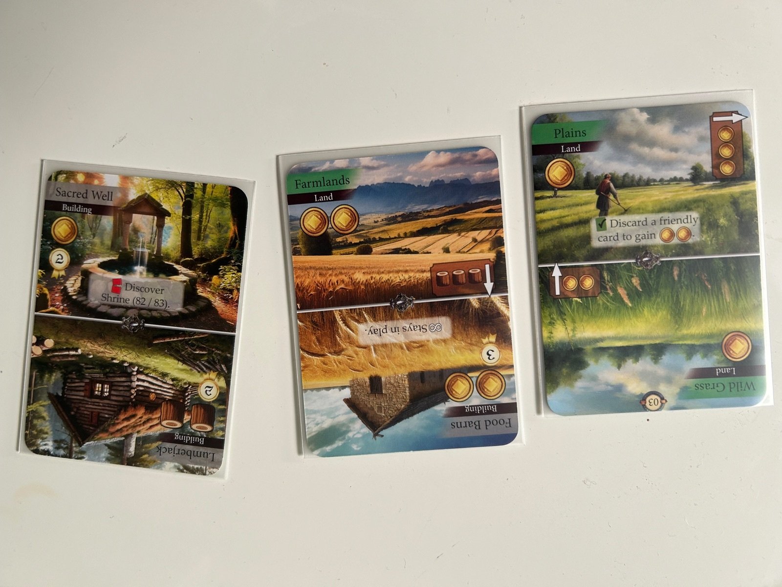 Cartas de Kingdom Legacy con edificios y recursos sobre la mesa